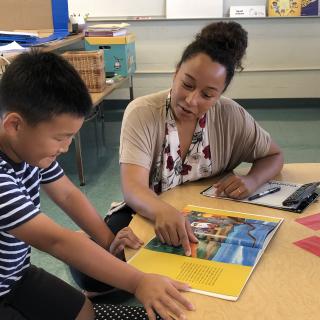 Teacher pointing at book with a student